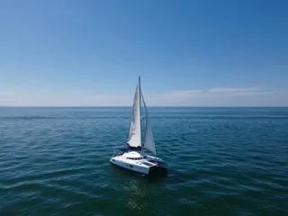 Slide: The Image of 2005 Lagoon 410 catamaran sailing on open sea under clear blue sky. - 0