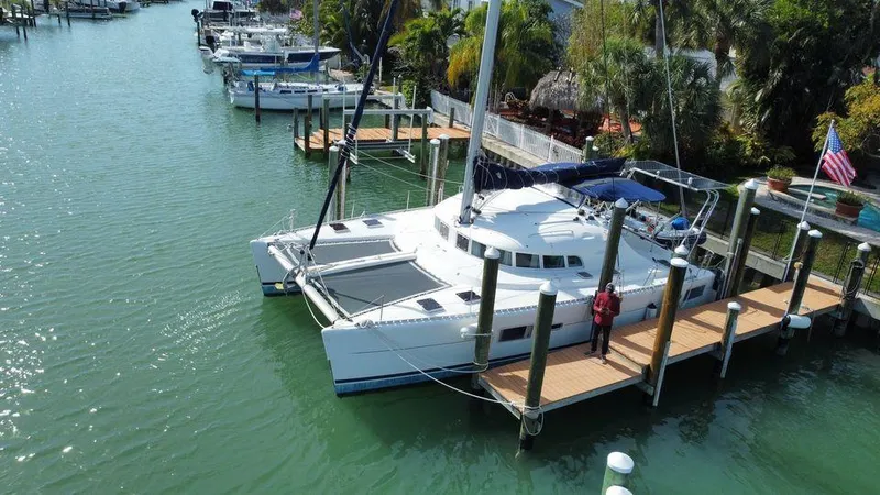 Slide: The Image of 2005 Lagoon 410 catamaran docked in a scenic marina with palm trees. - 1