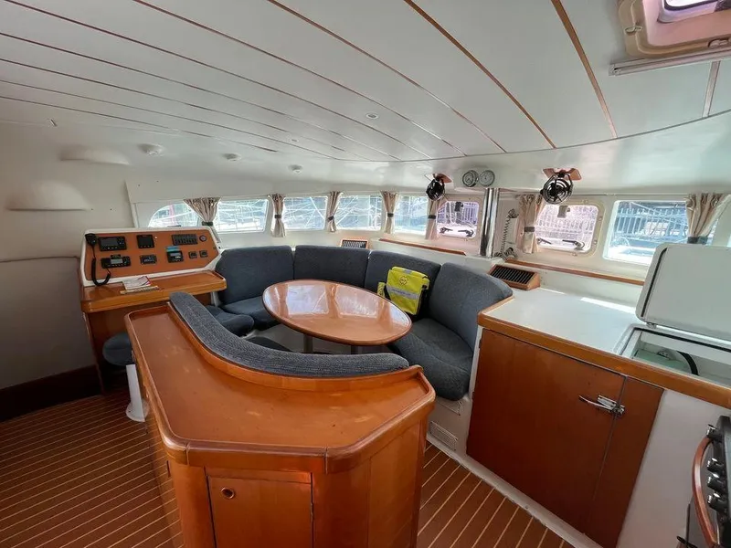 Slide: The Image of Interior of 2005 Lagoon 410 catamaran with wooden furnishings and cozy seating area. - 11