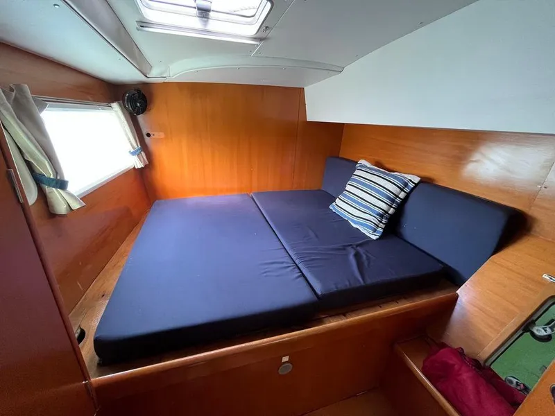 Slide: The Image of Lagoon 410 2005 model cabin with a cozy bed, window, and striped pillow. - 13