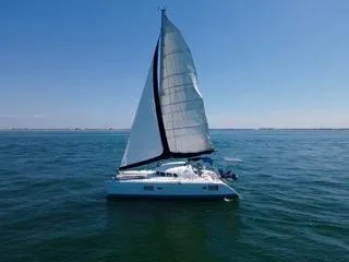Slide: The Image of 2005 Lagoon 410 catamaran sailing on open water under clear blue sky. - 17