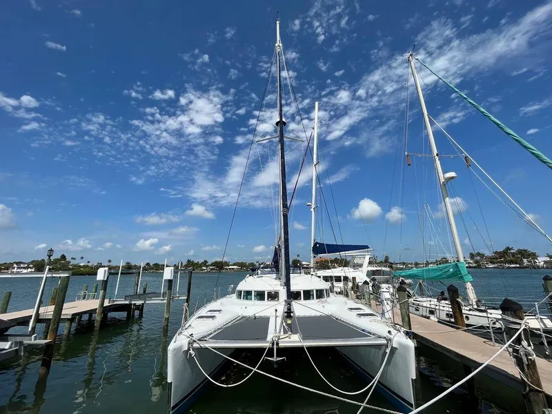 Slide: The Image of 2005 Lagoon 410 catamaran docked at a marina under a clear blue sky. - 4