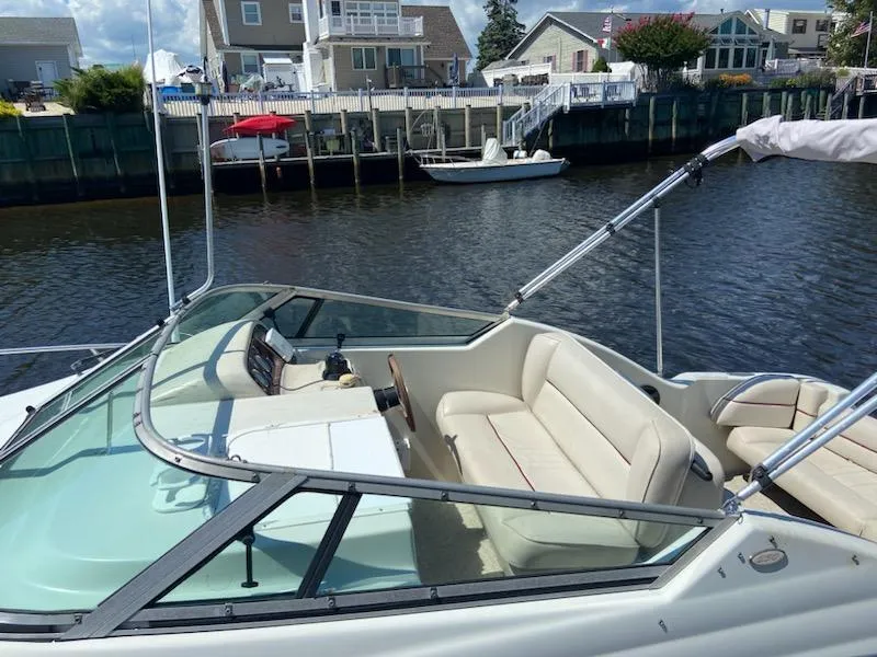 Slide: The Image of 1997 Crownline 250 CR boat with beige seating, docked by waterfront homes. - 5