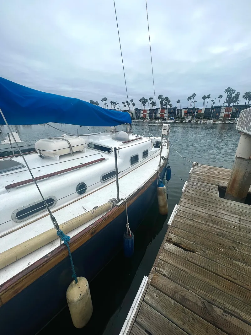 Slide: The Image of 1977 Van De Stadt Rebel 42 sailboat docked at a marina with a blue cover. - 11