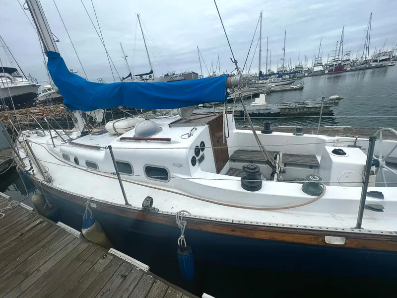 Slide: The Image of 1977 Van De Stadt Rebel 42 sailboat docked in a marina, featuring a blue sail cover. - 13