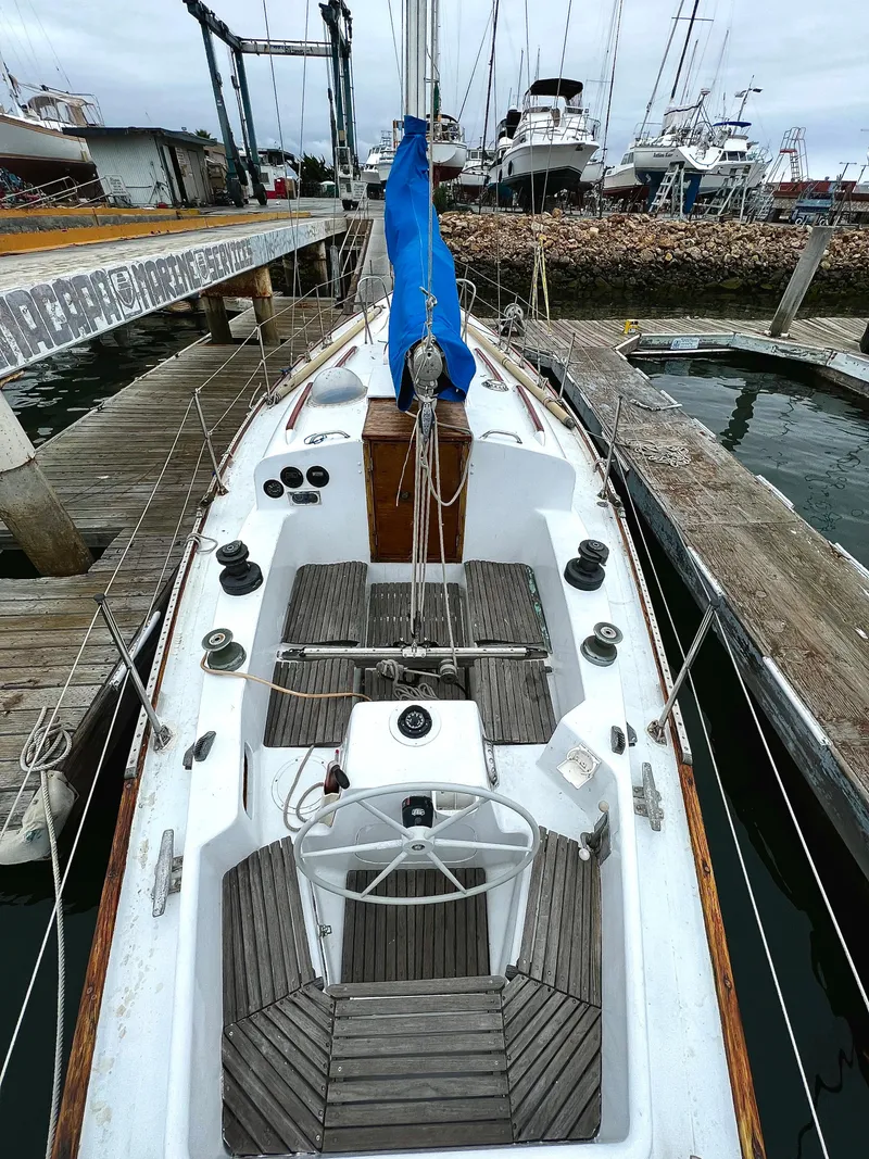 Slide: The Image of 1977 Van De Stadt Rebel 42 sailboat docked at a marina, showcasing its deck and steering wheel. - 21