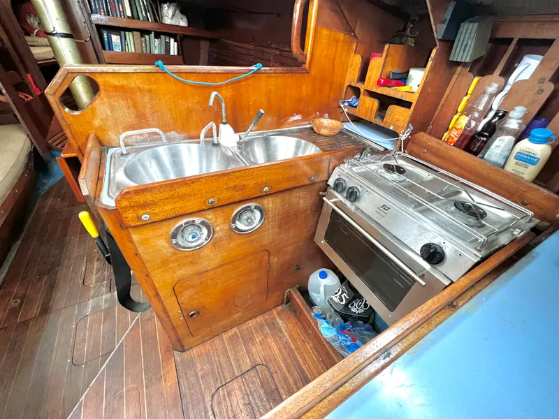Slide: The Image of 1977 Van De Stadt Rebel 42 yacht kitchen with wooden cabinetry, dual sink, and stove. - 32
