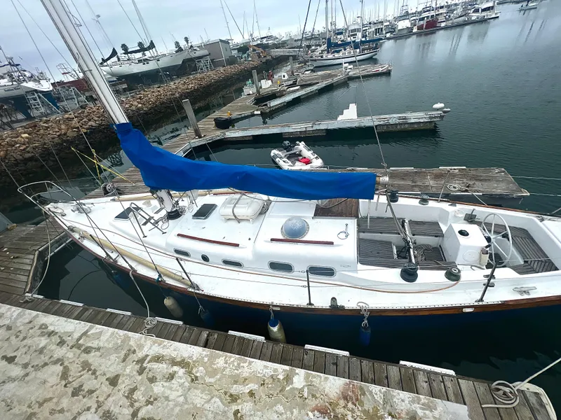 Slide: The Image of 1977 Van De Stadt Rebel 42 sailboat docked in a marina, featuring a blue sail cover. - 8