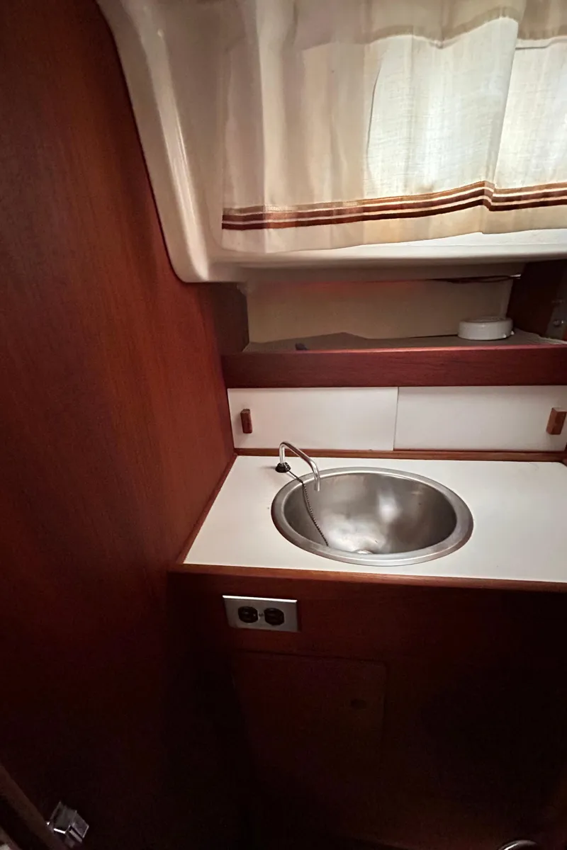 Slide: The Image of 1979 Sabre 28-2 sailboat interior sink area with wooden cabinetry and curtains. - 30