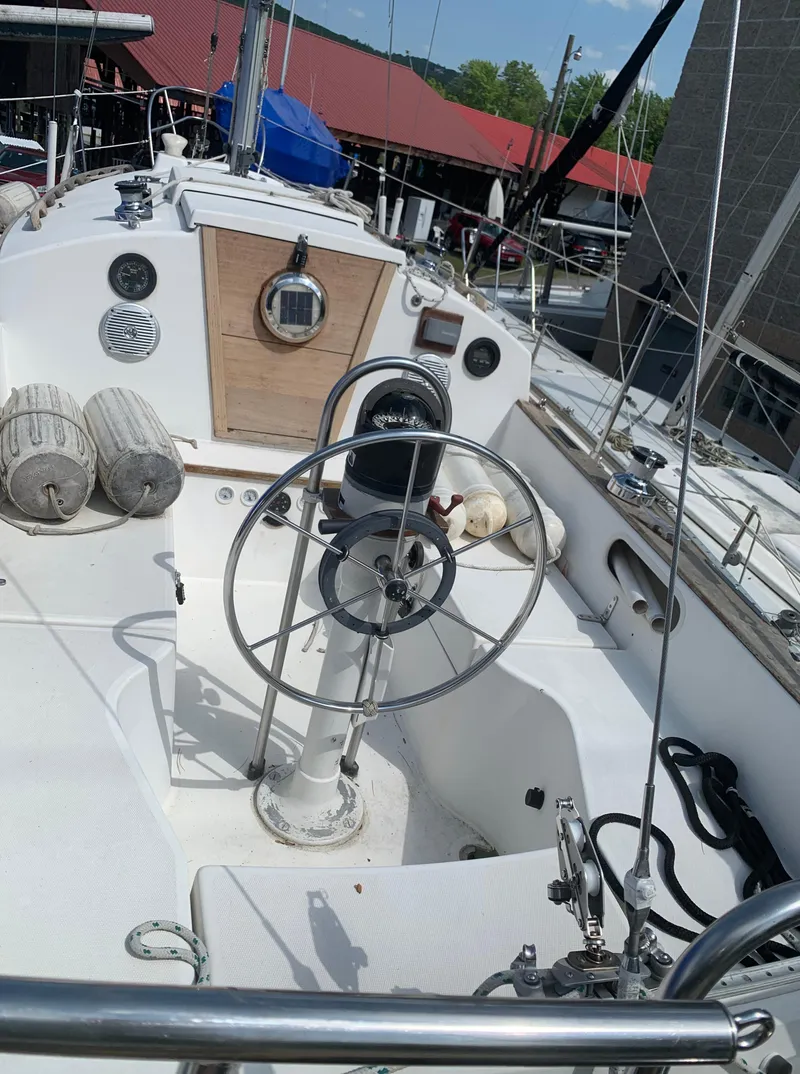 Slide: The Image of 1979 Sabre 28-2 sailboat cockpit with steering wheel and marina background. - 8