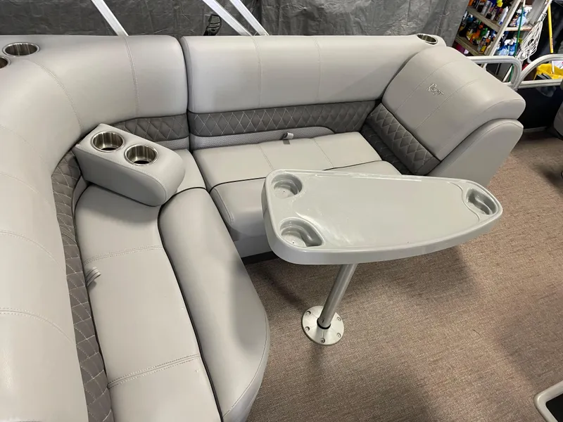 Slide: The Image of 2020 Ranger 220FC boat interior with gray seating and table featuring cup holders. - 15