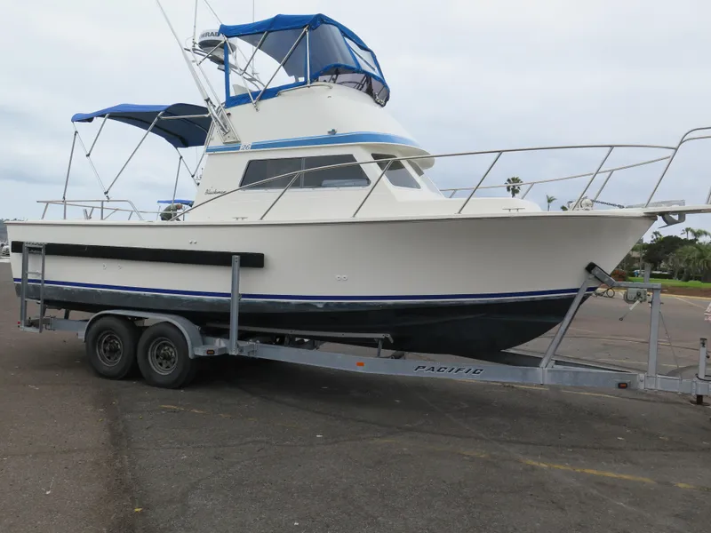 Slide: The Image of 1988 Blackman 26 Billfisher boat on trailer, featuring blue canopy and sleek design. - 34