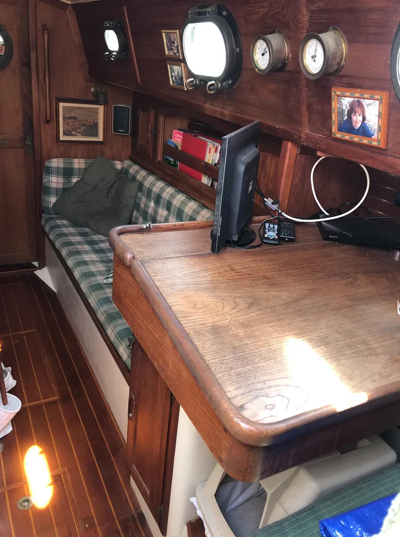 Slide: The Image of 1986 Pacific Seacraft Crealock 34 interior with wooden desk and plaid seating. - 23