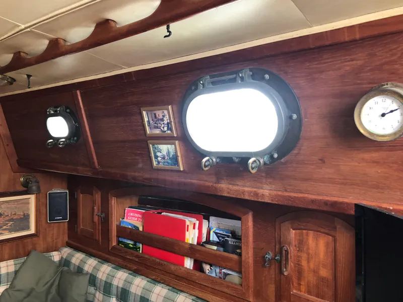 Slide: The Image of Interior of 1986 Pacific Seacraft Crealock 34 with portholes, wooden shelves, and plaid seating. - 37