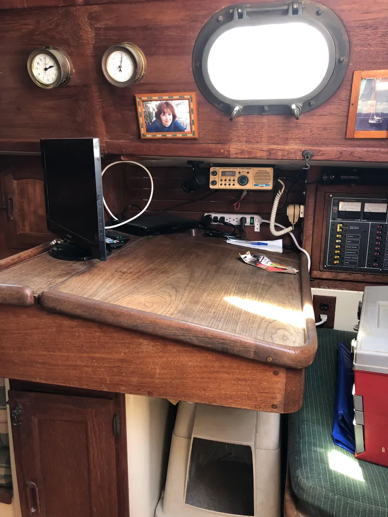 Slide: The Image of Navigation station inside 1986 Pacific Seacraft Crealock 34 sailboat, featuring wooden desk and marine electronics. - 38
