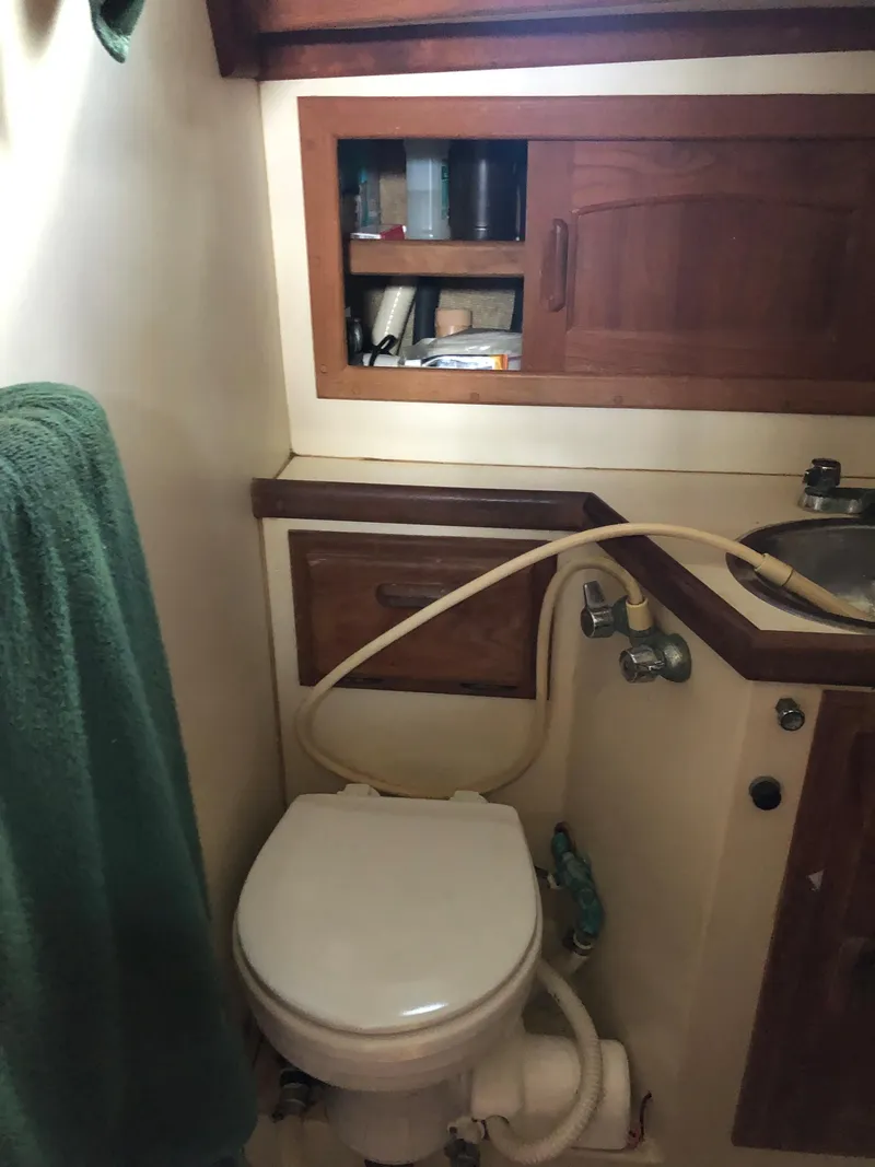 Slide: The Image of 1986 Pacific Seacraft Crealock 34 yacht bathroom with toilet, sink, and wooden cabinetry. - 44