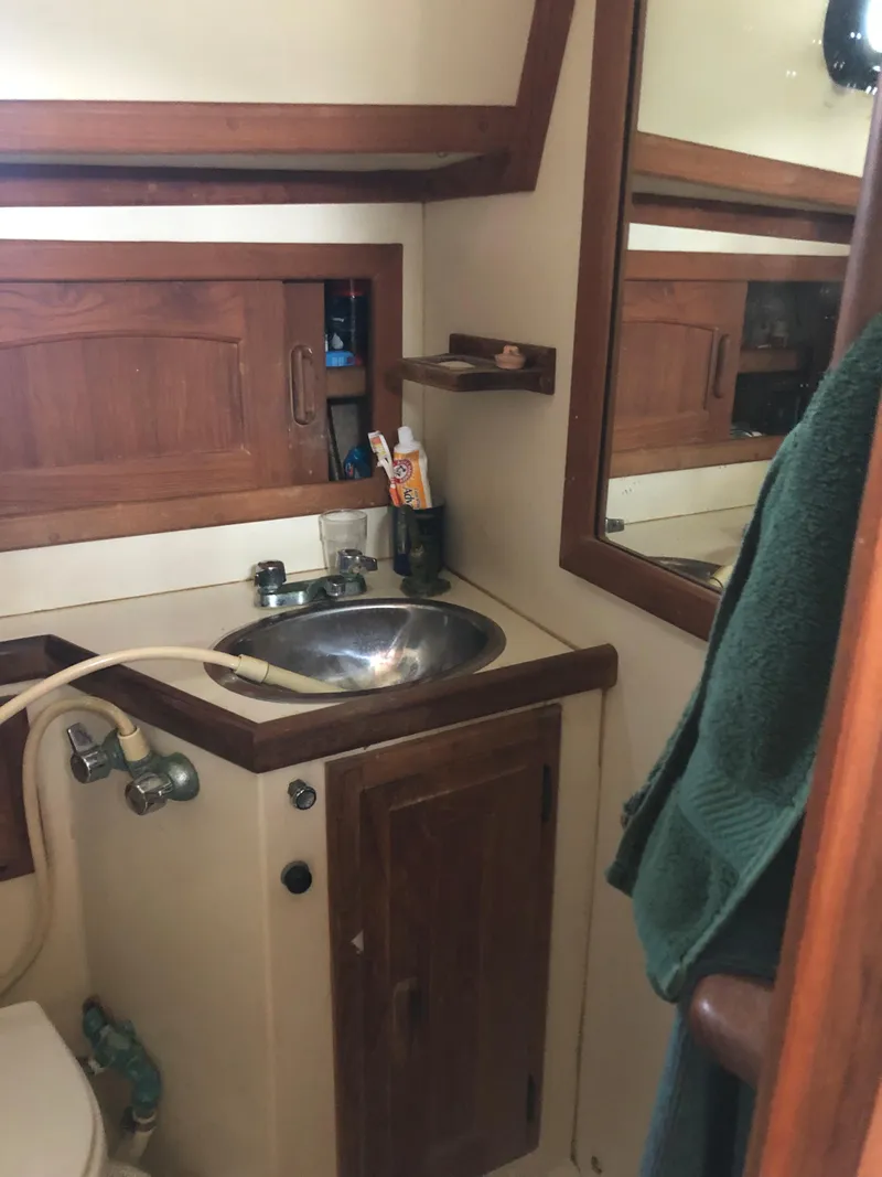 Slide: The Image of 1986 Pacific Seacraft Crealock 34 yacht bathroom with sink, mirror, and wooden cabinetry. - 45