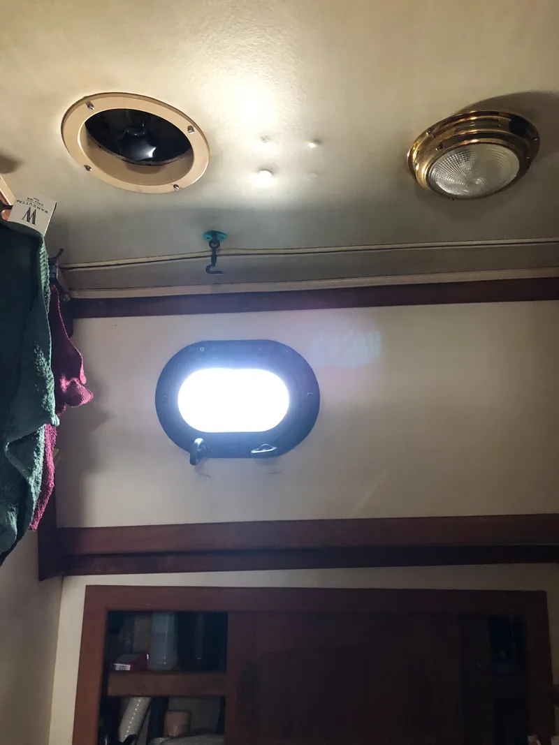 Slide: The Image of Interior of 1986 Pacific Seacraft Crealock 34 with porthole and ceiling fixtures. - 46