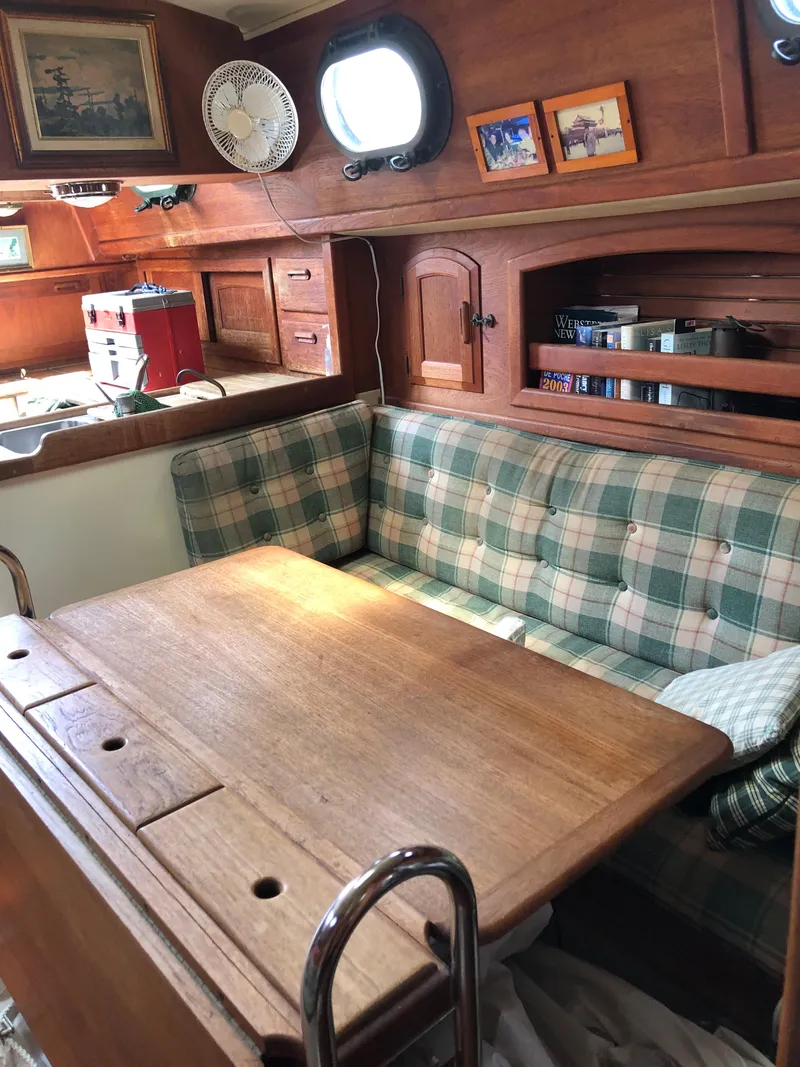 Slide: The Image of 1986 Pacific Seacraft Crealock 34 interior with plaid seating and wooden table. - 49