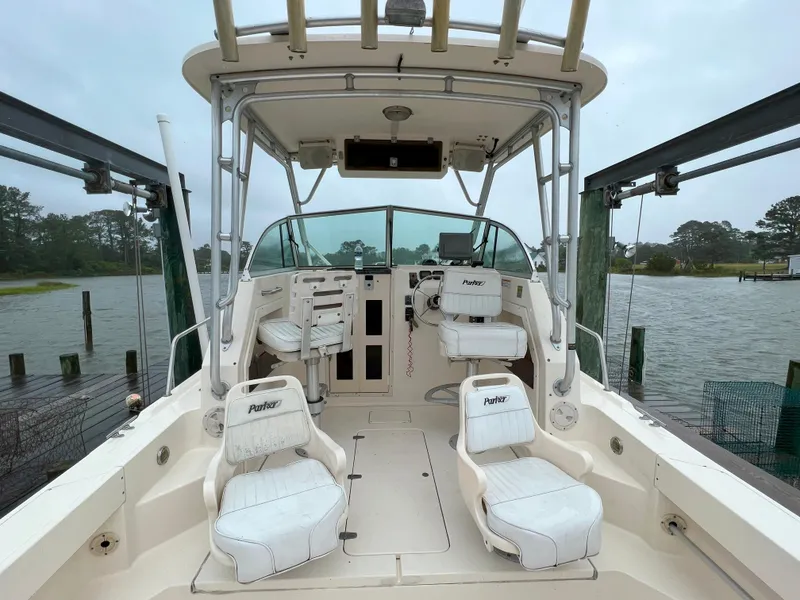 Slide: The Image of 2006 Parker 2310 Walkaround boat interior with seating and controls, docked by a lake. - 8