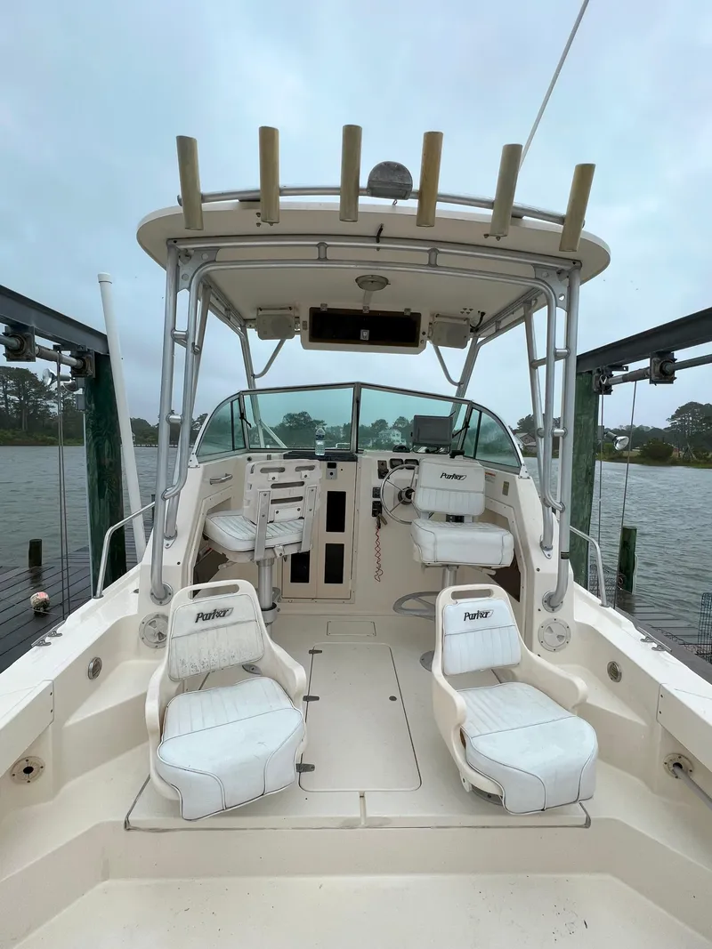 Slide: The Image of 2006 Parker 2310 Walkaround boat interior with seating and helm, docked by the water. - 9