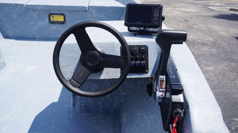 Slide: The Image of 2023 Griffis Fiberglass 16 Wide Side Console boat dashboard with steering wheel and navigation system. - 4