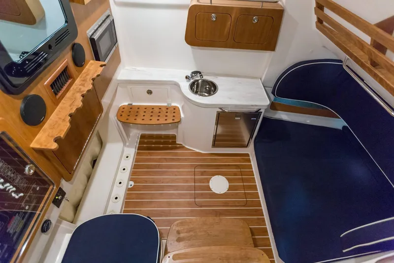 Slide: The Image of 2024 Grady-White Canyon 386 cabin interior with wood accents, sink, and seating. - 14