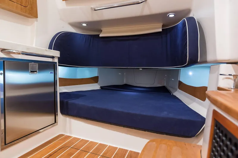 Slide: The Image of Interior cabin of 2024 Grady-White Canyon 386 with blue bedding and stainless steel fridge. - 15