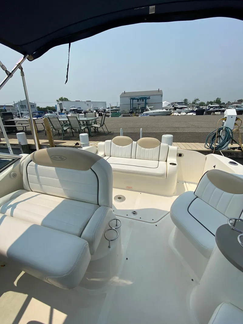 Slide: The Image of 2008 Sea Ray 240 Sundancer boat interior with white seating and marina background. - 14
