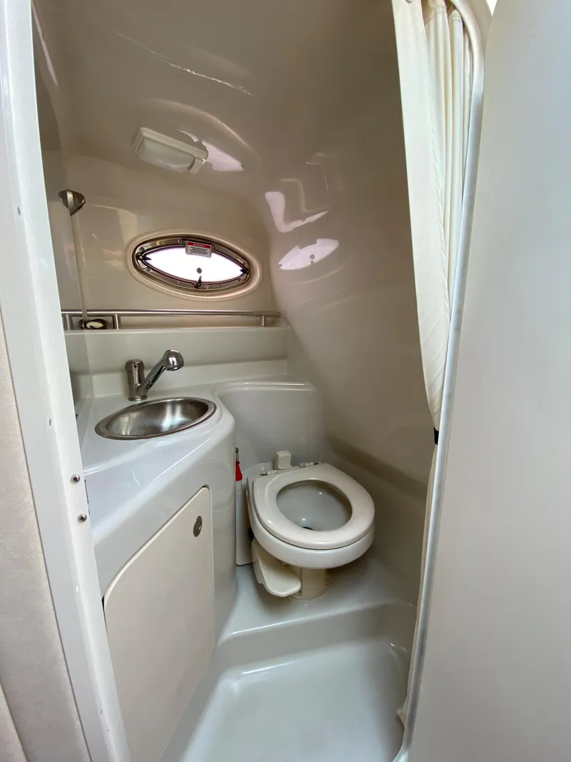 Slide: The Image of 2008 Sea Ray 240 Sundancer bathroom with sink, toilet, and porthole window. - 6