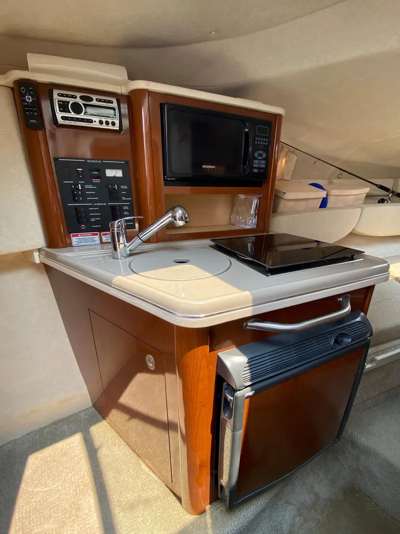 Slide: The Image of 2008 Sea Ray 240 Sundancer cabin kitchen with microwave, sink, and mini-fridge. - 7