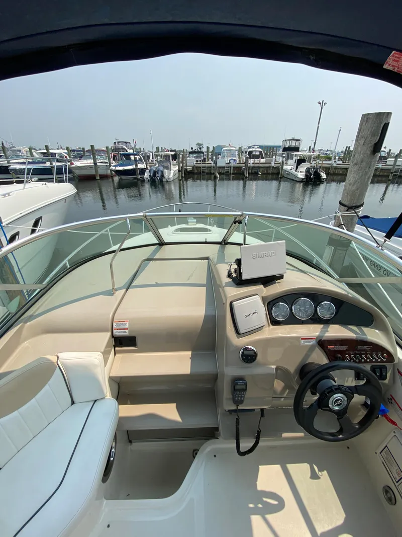 Slide: The Image of 2008 Sea Ray 240 Sundancer boat cockpit with steering wheel and marina view. - 9