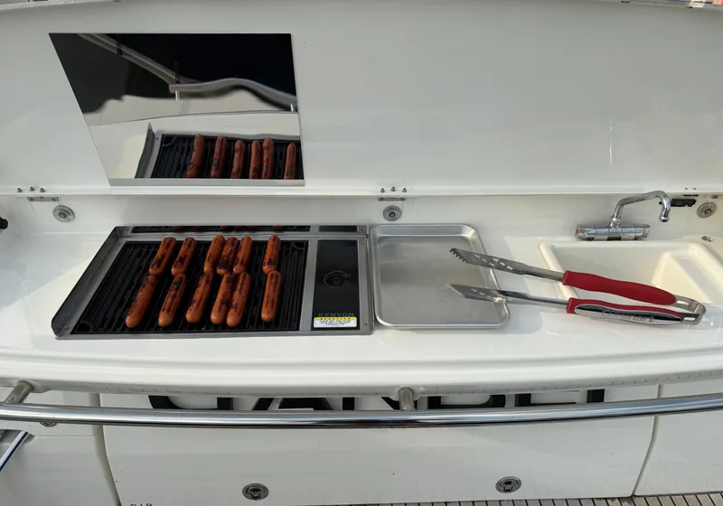 Slide: The Image of Grill with hot dogs on a Prestige 420S yacht, featuring tongs and a tray. - 12