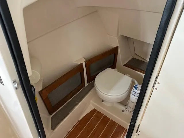 Slide: The Image of 2024 Grady-White Freedom 235 boat interior bathroom with wooden accents. - 5