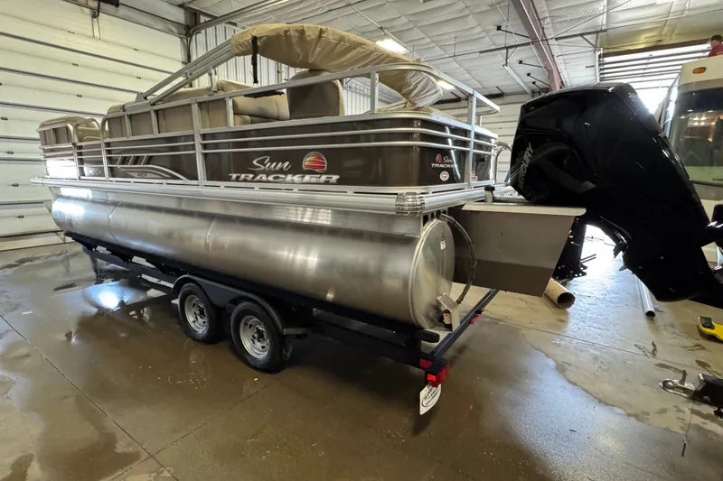 Slide: The Image of 2023 Sun Tracker SportFish 22 XP3 pontoon boat in a garage setting. - 5
