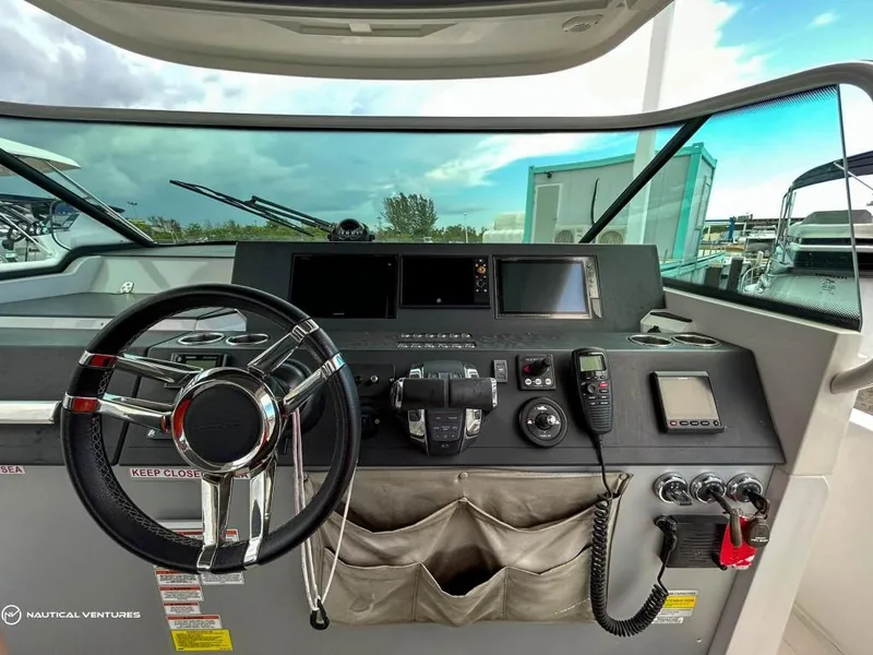 Slide: The Image of 2018 Axopar 37 Sun Top helm with steering wheel, navigation screens, and control panel. - 14