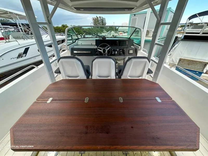 Slide: The Image of 2018 Axopar 37 Sun Top boat interior with wooden table and helm station. - 16