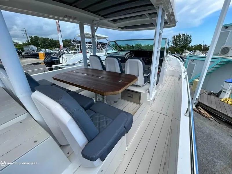 Slide: The Image of 2018 Axopar 37 Sun Top boat with spacious seating and wooden table on deck. - 18