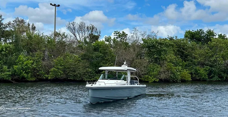 Slide: The Image of 2018 Axopar 37 Sun Top boat cruising on a calm river with lush greenery in the background. - 2