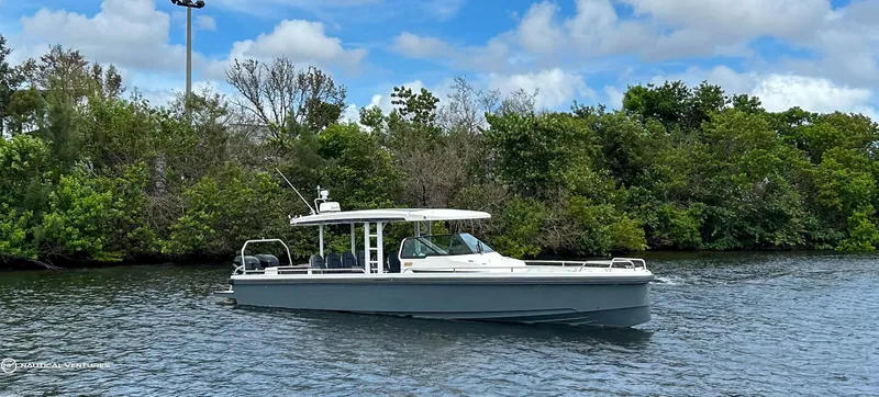 Slide: The Image of 2018 Axopar 37 Sun Top boat cruising on a river with lush greenery in the background. - 6