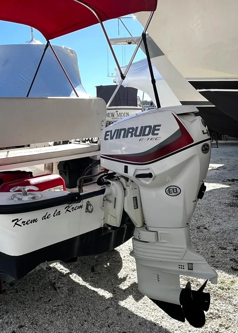 Slide: The Image of 2002 Boston Whaler 130 Sport with Evinrude outboard motor, docked under a red canopy. - 3