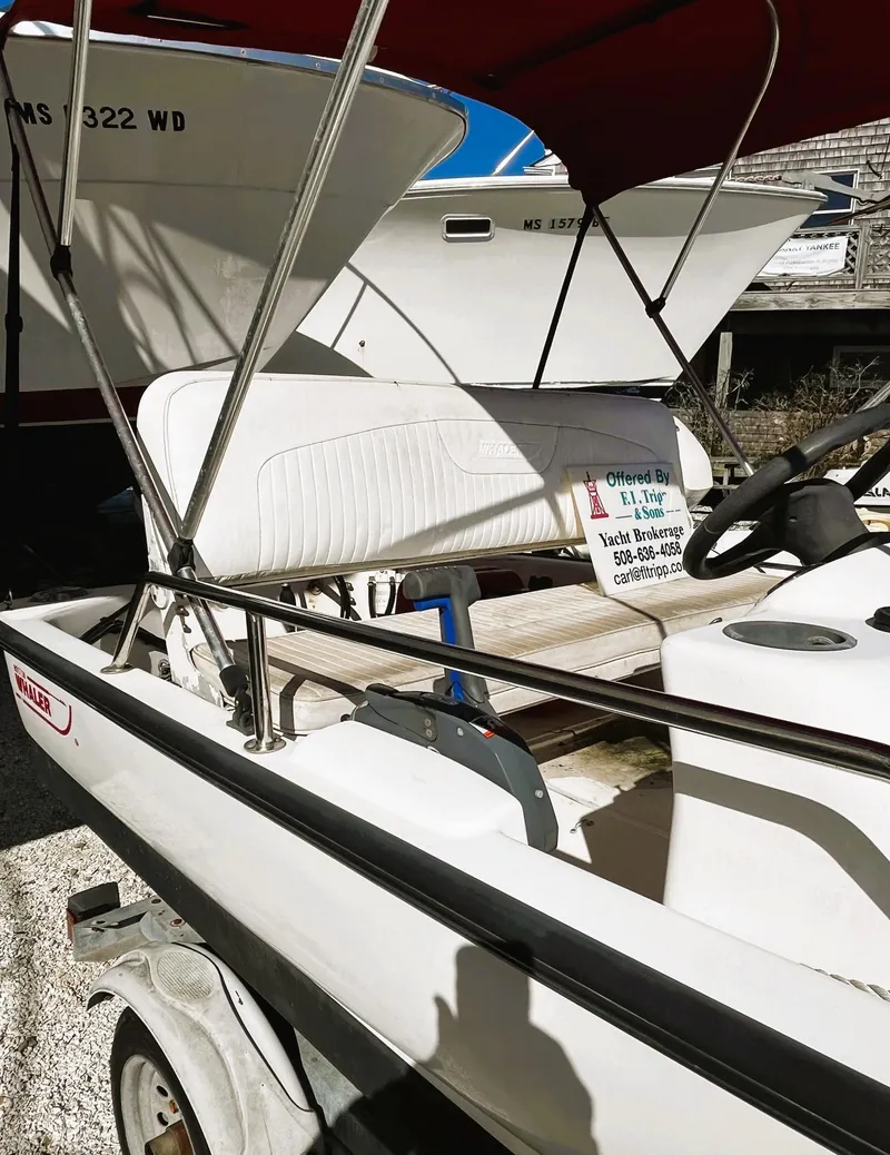 Slide: The Image of 2002 Boston Whaler 130 Sport boat with canopy, parked on a trailer. - 4