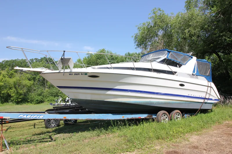 The Image of 1994 Bayliner 3055 Sunbridge on trailer in grassy area. - 1