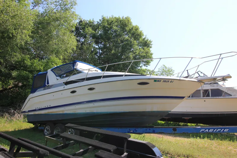 Slide: The Image of 1994 Bayliner 3055 Sunbridge boat on a trailer, surrounded by trees. - 3