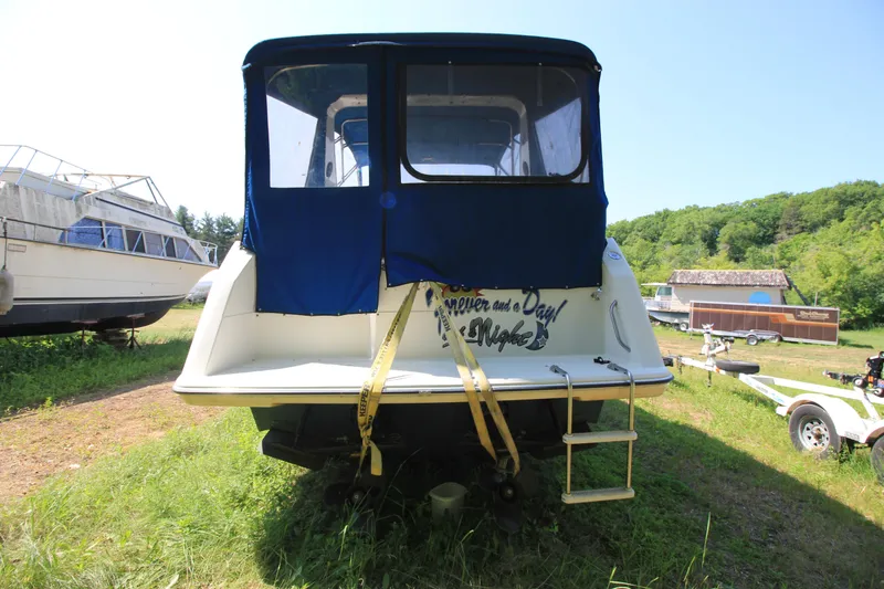 Slide: The Image of 1994 Bayliner 3055 Sunbridge boat with blue canvas cover, parked on grass. - 4