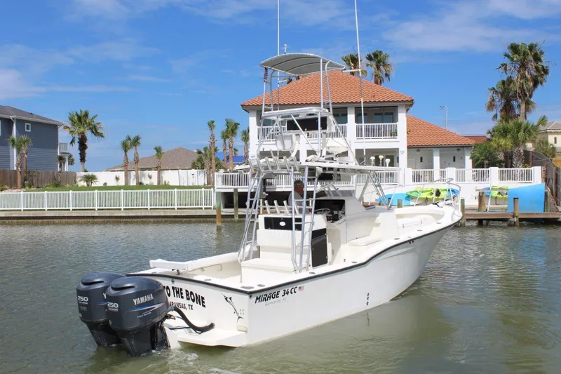 Slide: The Image of 1999 Mirage 34 Walk Around boat docked near waterfront homes. - 4