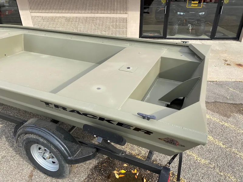 Slide: The Image of 2023 Tracker Grizzly 1754 Jon boat on a trailer, parked outside a building. - 2