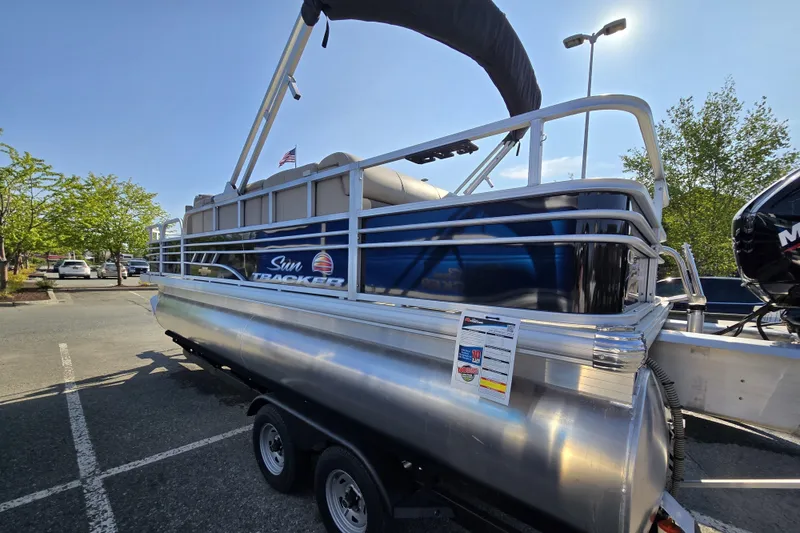 Slide: The Image of 2023 Sun Tracker SportFish 20 DLX pontoon boat on trailer in parking lot. - 2