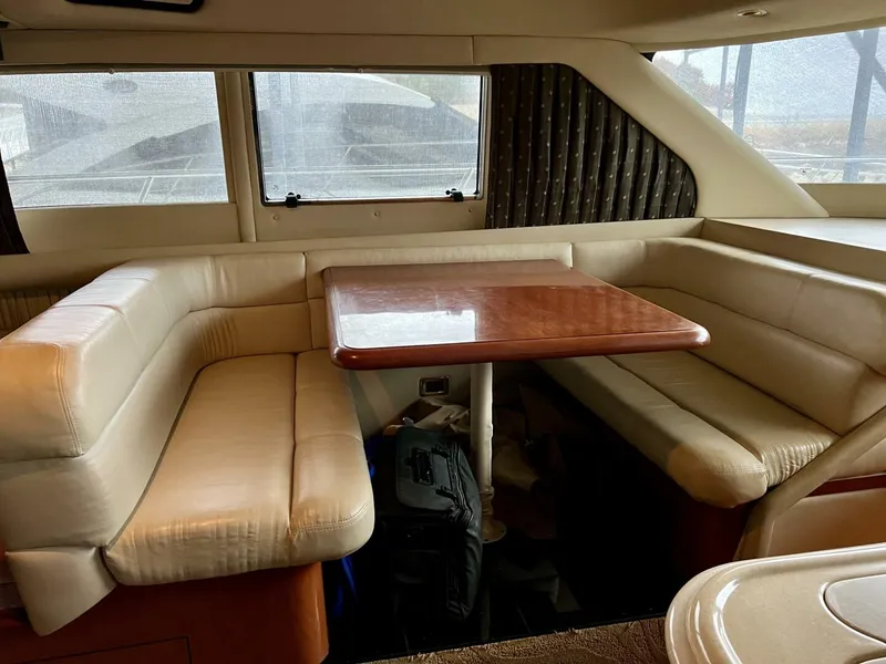 Slide: The Image of 2001 Sea Ray 56 Sedan Bridge interior dining area with leather seating and wooden table. - 7