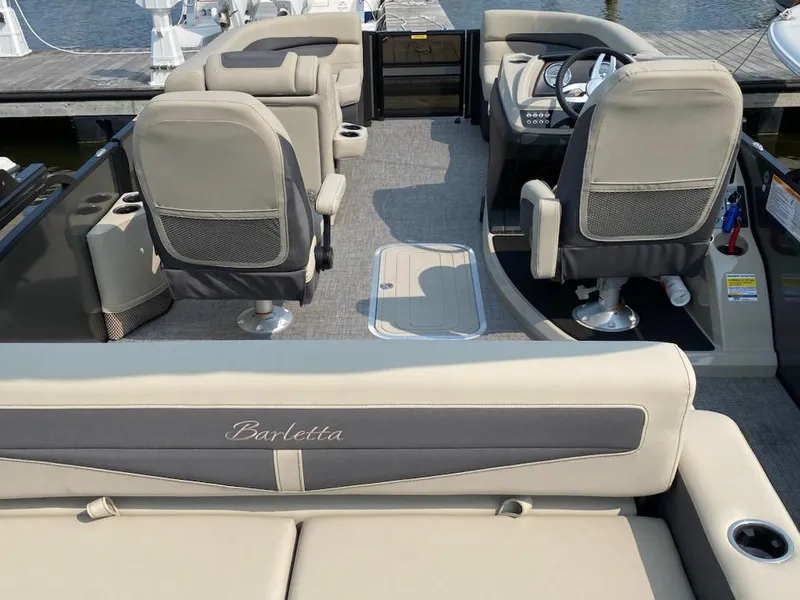 Slide: The Image of 2023 Barletta C22UC pontoon boat interior with beige seating and steering console. - 4